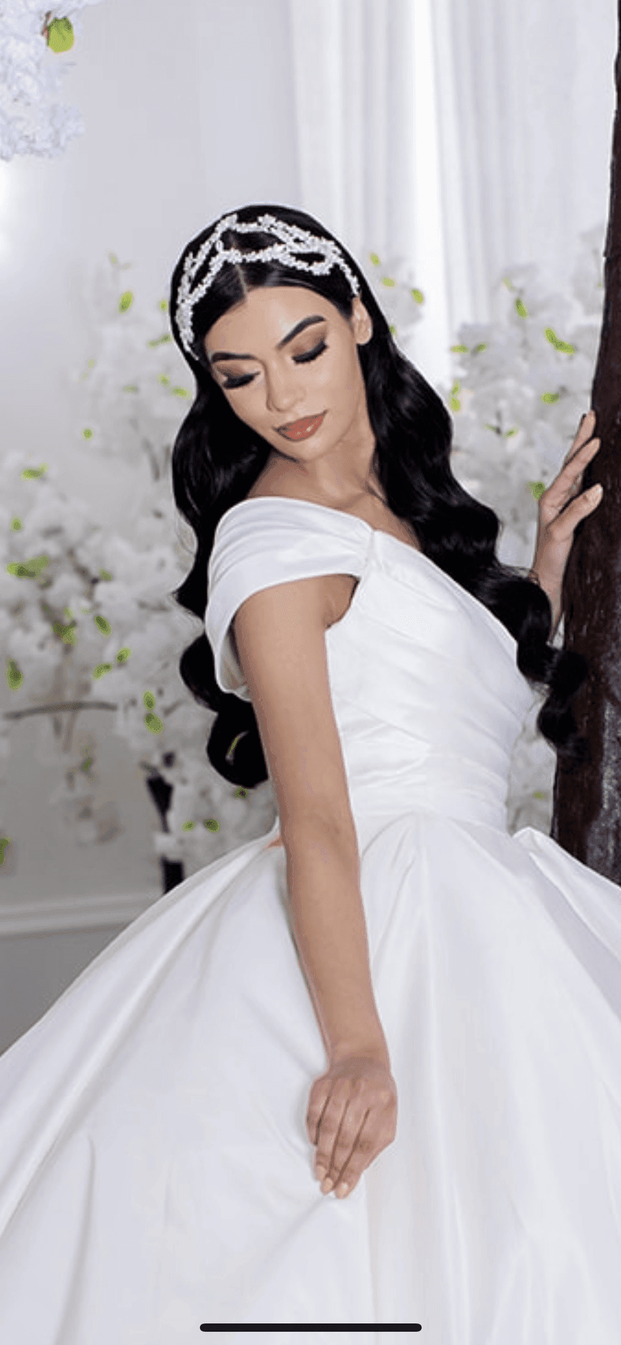 Woman in an elegant white wedding dress with a jeweled headpiece, standing gracefully.